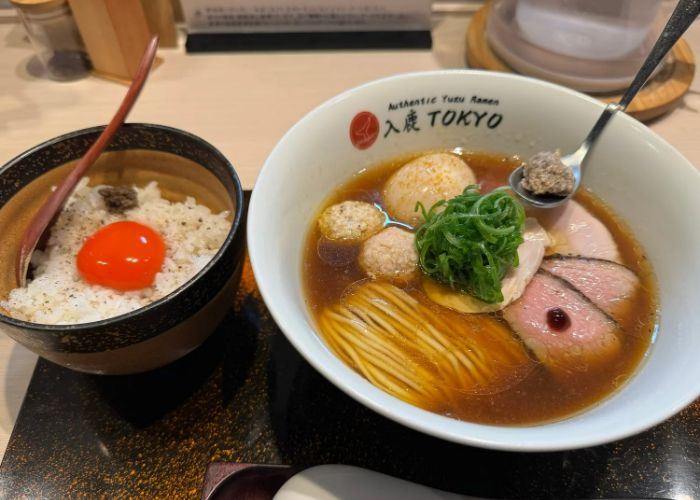 A bowl of ramen at Iruca Tokyo Roppongi, a Michelin star ramen restaurant in Tokyo. There's also a bowl of rice with egg yolk to the side.